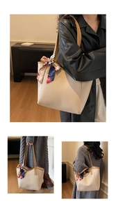 Detail view of cream tote bag with brown trim and stylish patterned handle scarf