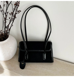 Detail of black suede and patent leather shoulder bag featuring a heart charm