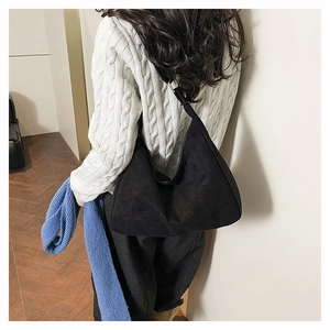 Detail of black crescent shoulder bag in matte finish with golden hardware buckle