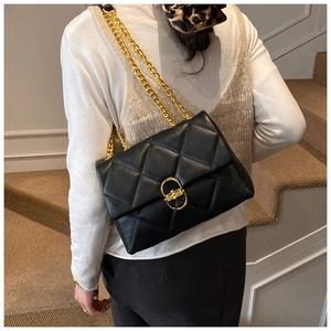 Detail of black quilted chain bag featuring gold hardware and classic diamond stitch