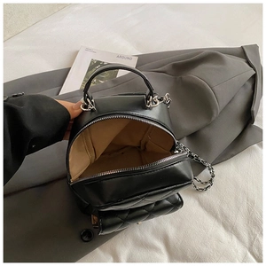 Detail of black quilted mini backpack with silver metal handle and chain strap on blazer