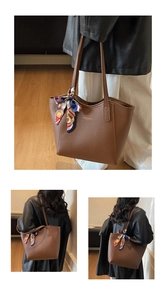 Detail of a brown leather tote with gold text and a decorative floral scarf on the handle