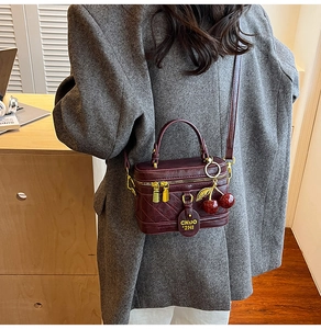 Vue détaillée du sac boîte en cuir matelassé rouge foncé avec pendentif cerise et or