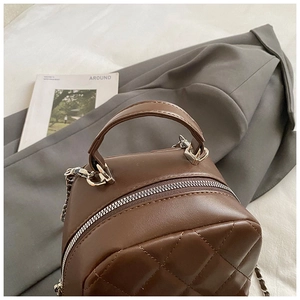 Detail of coffee brown quilted mini handbag with silver chain strap and top handle
