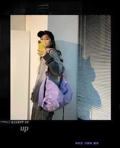 Detailed view of purple drawstring shoulder bag shown in a mirror selfie with casual style