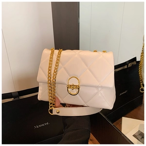 Close-up of white quilted leather texture with gold D-shaped metal lock and chain strap