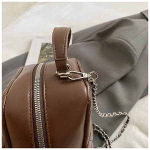 Close-up of quilted leather backpack showing silver chain hardware and top handle detail