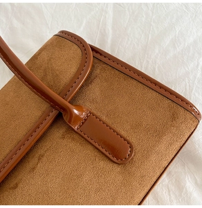 Detail view of brown suede and leather textures with precise stitching on shoulder bag