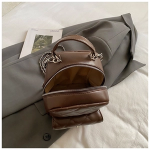 Detail of a brown quilted mini backpack with silver metal chain on a grey blazer