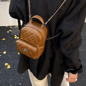 Detail of brown quilted mini backpack with silver metal chain straps and twist lock closure