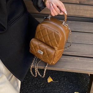 Close-up of quilted pattern and silver chain strap on a stylish brown backpack
