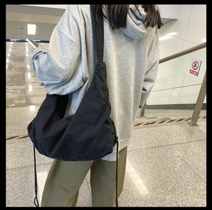 Close-up of a large black canvas crossbody bag with a wide strap for daily casual use