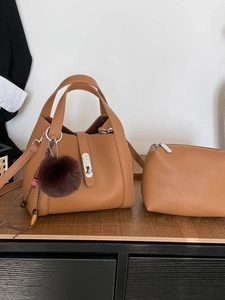 Vintage brown lychee grain leather bucket bag with inner pouch and pompom charm on wood