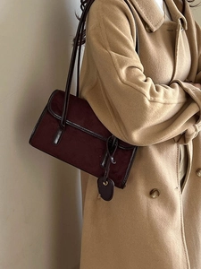 Vintage burgundy underarm bag in suede and leather worn with a camel coat