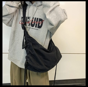 Detail view of large black canvas messenger bag with drawstring bottom and wide shoulder strap