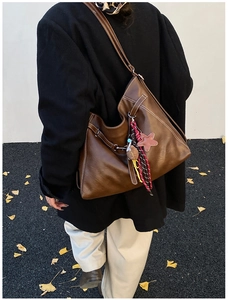 Détail du sac cabas en similicuir marron avec surpiqûres blanches et pendentif en étoile