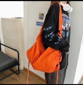 Detail of bright orange canvas messenger bag with adjustable strap and drawstring design