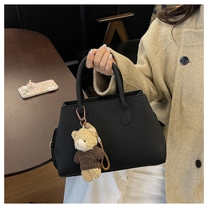 Dettaglio di borsa in pelle martellata nera con un tenero ciondolo a forma di orsetto