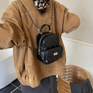 Detail view of the quilted texture and chain strap on the black mini backpack for women