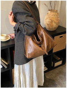 Detail view of large brown tote bag with contrast stitching and adjustable buckle strap