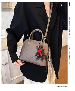 Close-up of brown pebbled leather shell bag featuring a cute decorative bear charm detail