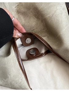 Close-up of khaki canvas tote bag with magnetic snap closure and leather trim detail