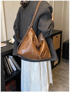 Détail d'un sac hobo marron avec surpiqûres blanches contrastées dans un cadre chic