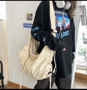 Detail of off-white canvas hobo bag showing adjustable strap and soft textured material