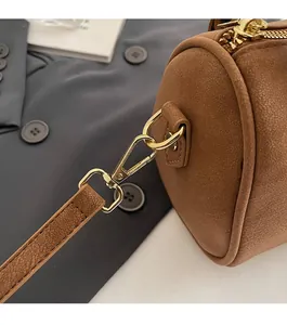 Detail of high-end brown Boston bag featuring polished gold hardware and premium leather texture