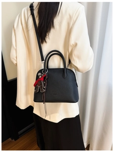 Detail of black lychee grain leather shell bag with cute bear charm and shoulder strap