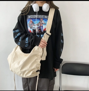 Detail of off-white canvas crossbody bag with wide shoulder strap and drawstring design