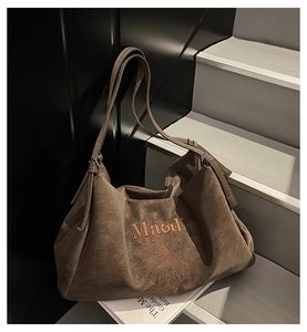 Close-up of vintage brown tote bag featuring orange daisy embroidery and texture