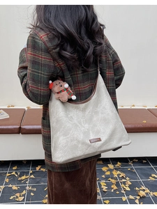 Detail of a large retro faux leather tote bag with a cute plush bear charm on a strap
