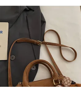 Detail of adjustable shoulder strap with gold buckle on brown faux suede Boston bag