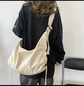 Detailed back view of a beige canvas crossbody bag with pleated texture and wide strap