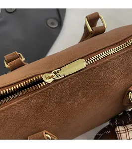 Close-up of golden zipper hardware and lychee pattern leather on brown Boston bag