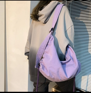 Detail of purple canvas crossbody bag with adjustable wide shoulder strap and drawstring