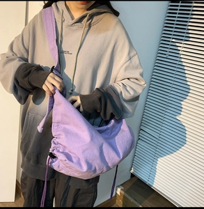 Close-up of lavender canvas crossbody bag with pleated cloud design and drawstring detail