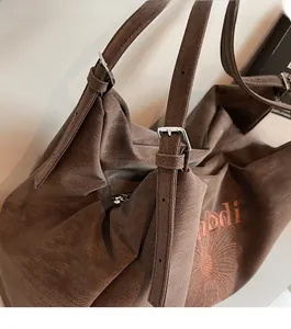 Detail of floral embroidery and adjustable silver buckle on brown tote bag