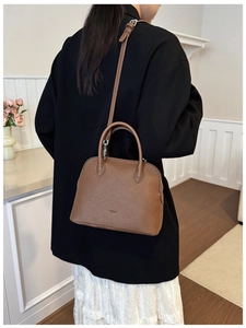 Detailed view of a brown lychee pattern shell bag with top handles and adjustable strap