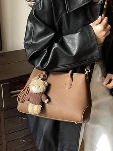 Borsa a secchiello in pelle marrone con ciondolo a orsetto in una posa lifestyle