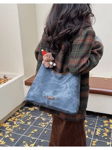 Spacious blue denim-style tote bag with cute teddy bear charm worn with plaid coat