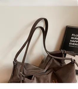 Detail of comfortable shoulder strap and embroidery on dark brown suede tote bag