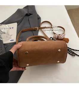 Detailed view of bottom metal rivets and fuzzy bow charm on brown Boston bag