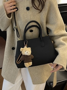 Elegante borsa a secchiello nera con ciondolo a orsetto indossata da modella