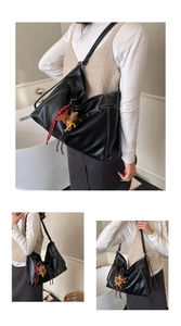 Detail of black tote bag featuring white contrast stitching and cute decorative charms