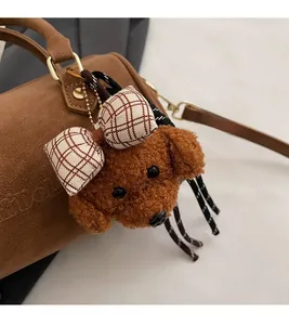 Close-up of cute caramel plush puppy bag charm with red checkered bow on Boston bag