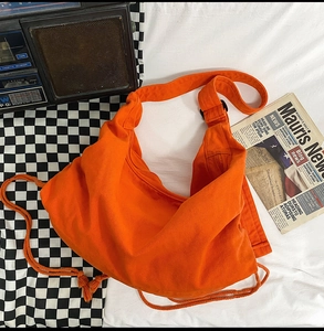Detail of bright orange canvas crossbody bag with wide strap on retro background