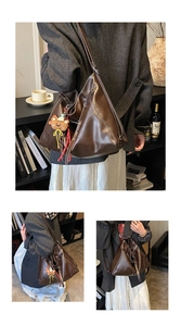 Detail of dark brown triangular leather tote with contrast stitching and bear charm