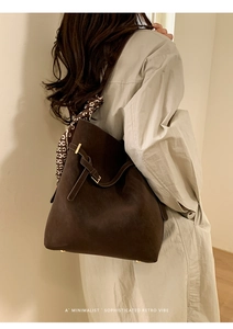 Detail of dark brown suede bucket bag featuring a silk scarf wrap and metal buckle